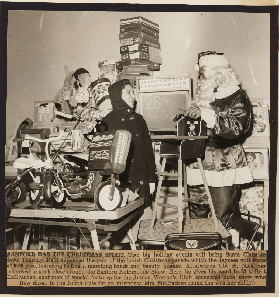 A newspaper clipping with an image of a Sanford Junior Woman's Club member smiling at Santa at the annual Sanford Automobile Show.